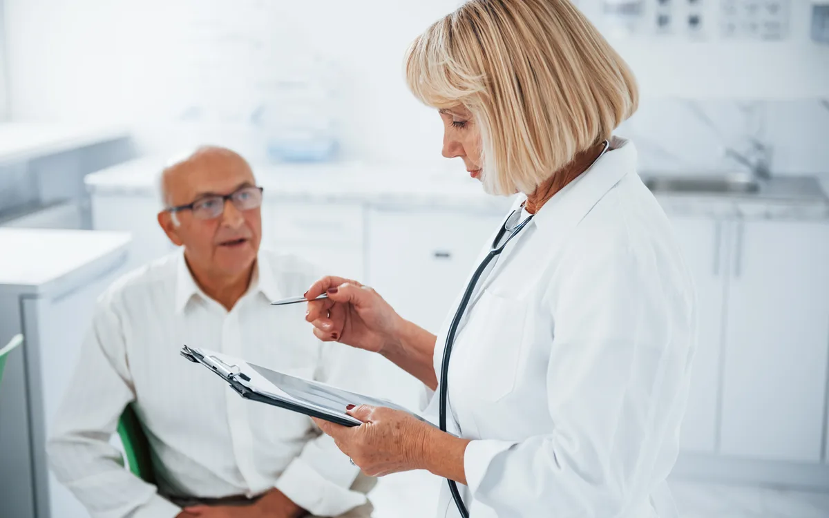 Ärztin bespricht Unterlagen mit einem Patienten in der Praxis
